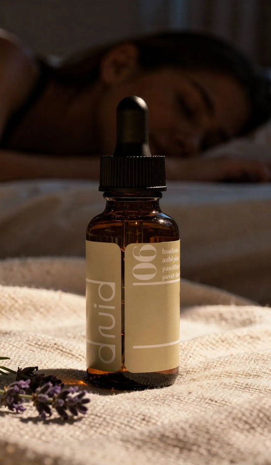 Flacon ambré avec pipette noir sur tissu beige, étiquette beige minimaliste "p 'nula" et texte, en arrière-plan une femme dormir.