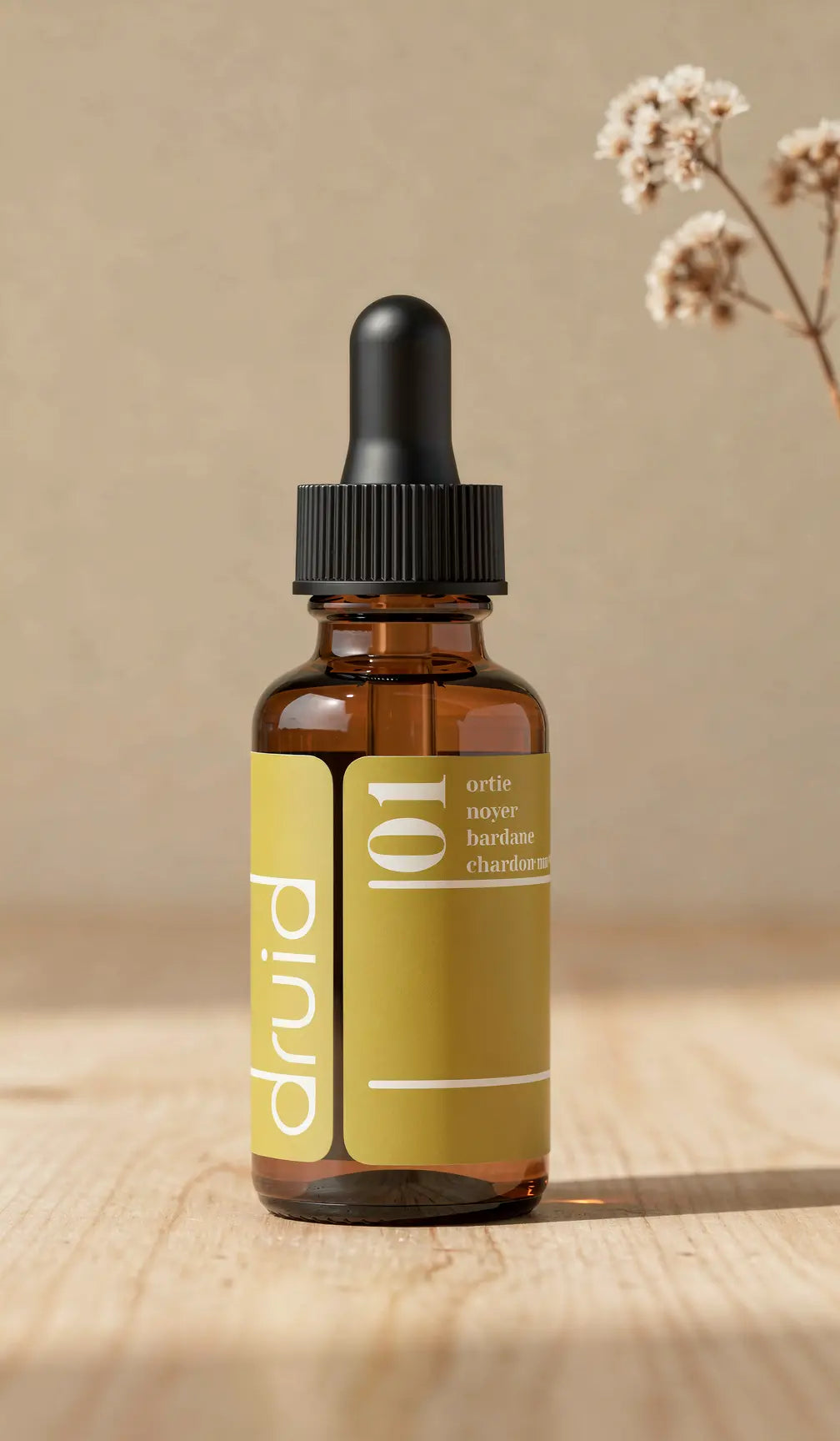 Bouteille en verre ambré avec compte-gours dropper noir et étiquette jaune olive affichant “Potion 01”; texture bois et plantes en arrière-plan.